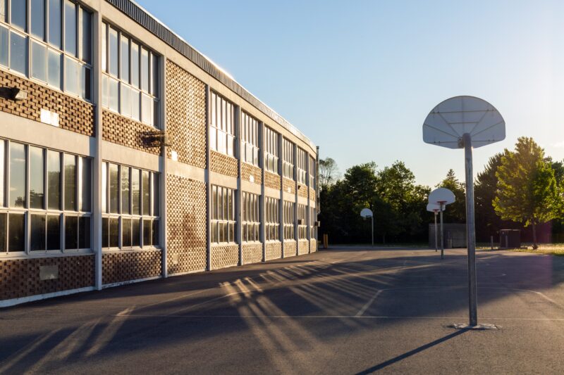 Schoolyard,With,Basketball,Court,And,School,Building,Exterior,In,The