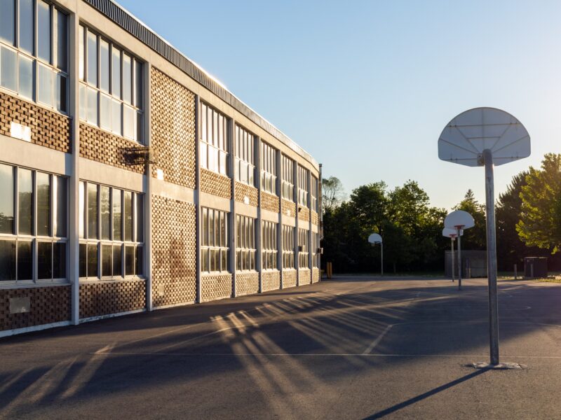 Schoolyard,With,Basketball,Court,And,School,Building,Exterior,In,The