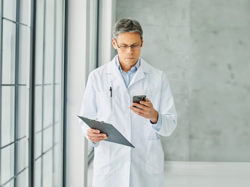 Portrait,Of,A,Middle,Aged,Doctor,Using,Smartphone,In,His